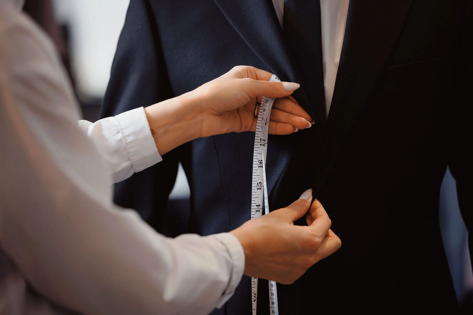 A Conxeppt tailor measuring a jacket by hand