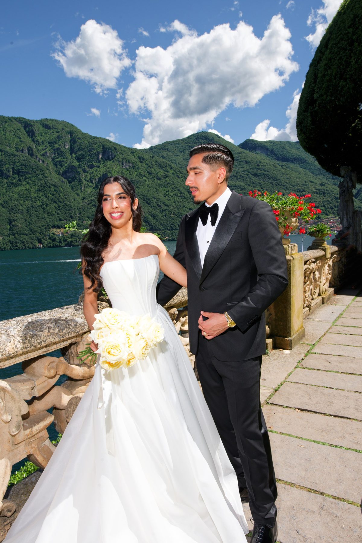 The couple on a balcony above the lake, mountains beyond