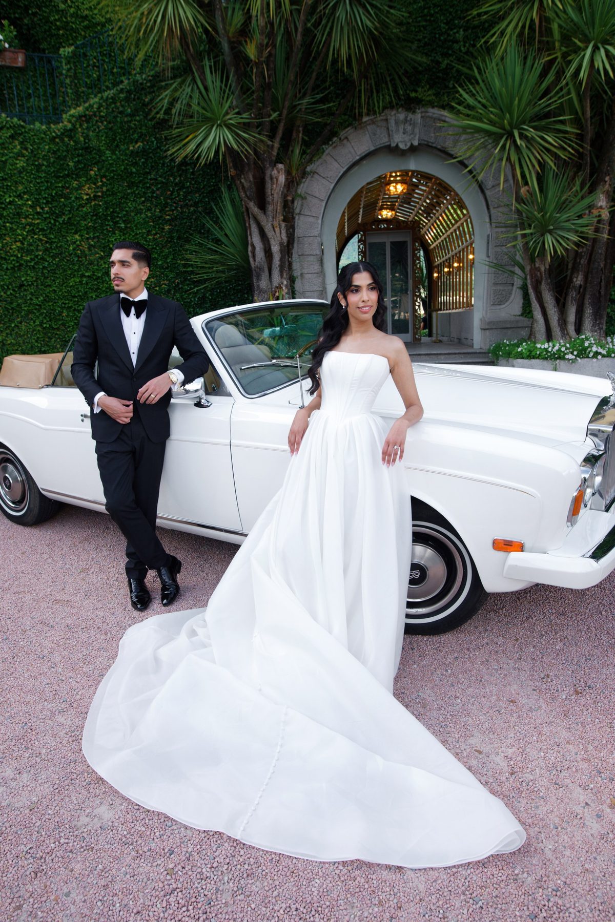 The couple beside a white classic car at the villa entrance